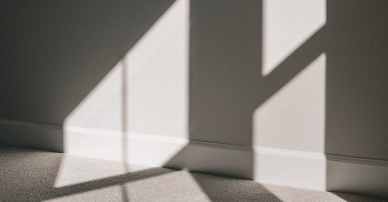 Housing Cooperatives - Shadow of window with glazing bars on wall and floor of minimal apartment in sunlight