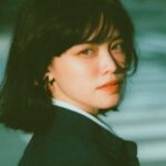 Smart City Initiatives - Side view of confident young Asian female entrepreneur in elegant outfit standing on city street and looking at camera