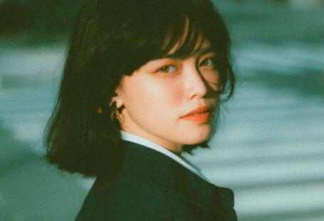 Smart City Initiatives - Side view of confident young Asian female entrepreneur in elegant outfit standing on city street and looking at camera