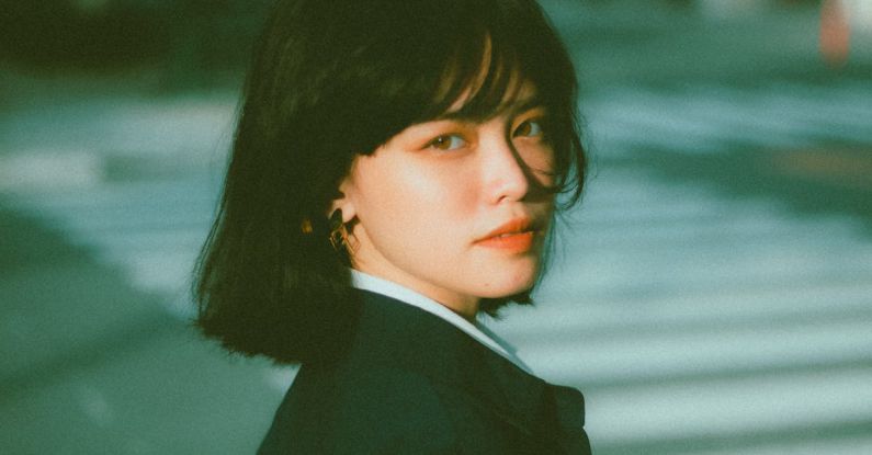 Smart City Initiatives - Side view of confident young Asian female entrepreneur in elegant outfit standing on city street and looking at camera