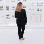 Historical Preservation - Woman standing in modern museum with pictures on walls