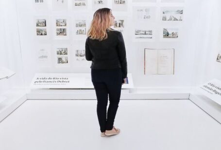 Historical Preservation - Woman standing in modern museum with pictures on walls