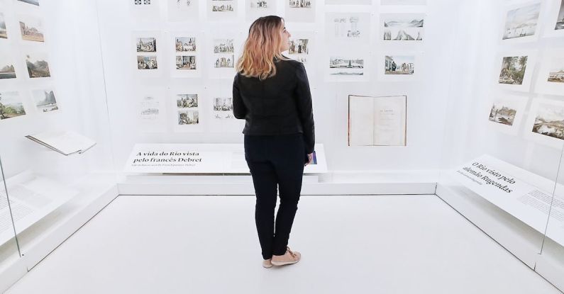 Historical Preservation - Woman standing in modern museum with pictures on walls