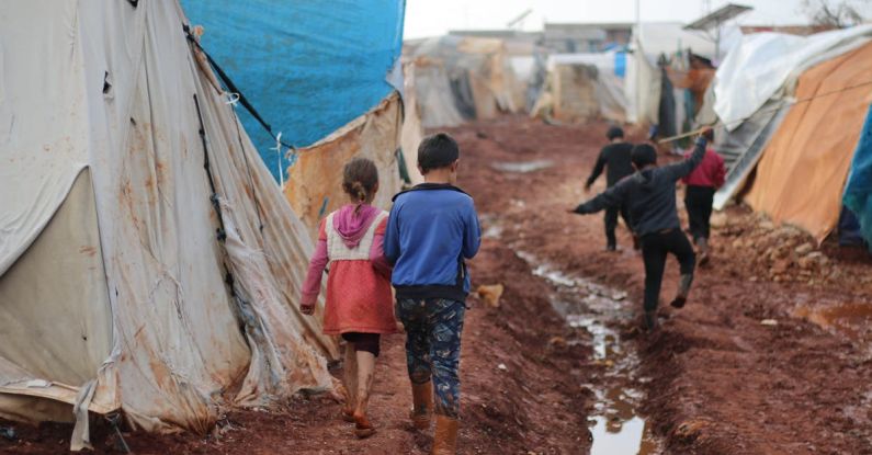 Flood-Prone Areas - Children walking on dirty street with tents