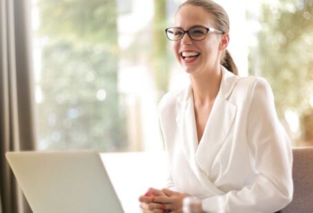 Telecommuting - Laughing businesswoman working in office with laptop