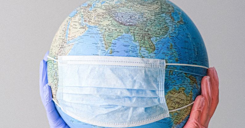 Pandemic - Hands With Latex Gloves Holding a Globe with a Face Mask