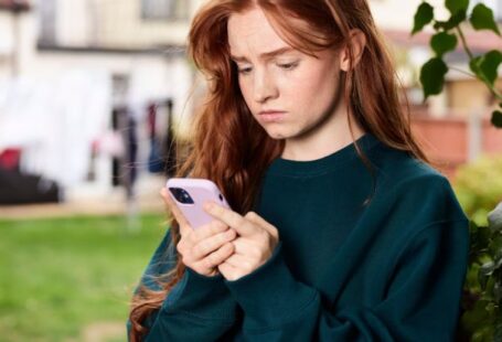 Digital Divide - Redhead Woman Standing under Tree Using Phone