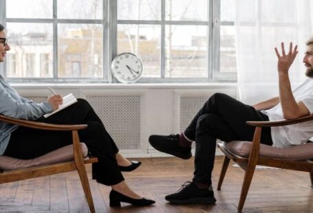 Mental Health Support - Person in Black Pants and Black Shoes Sitting on Brown Wooden Chair