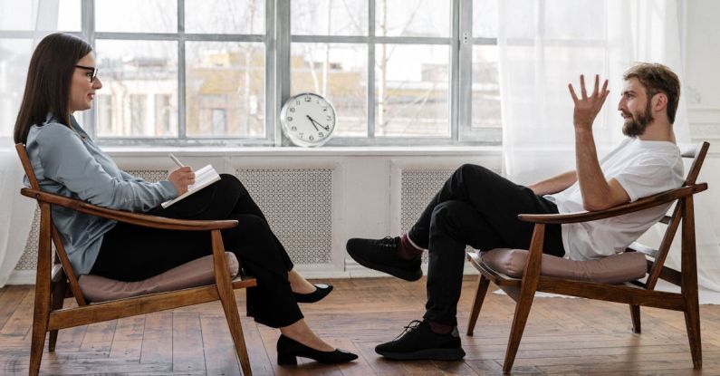 Mental Health Support - Person in Black Pants and Black Shoes Sitting on Brown Wooden Chair